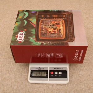 Detailed view of musical Christmas TV lantern showing 1331g weight on a digital scale