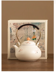 Detail of ceramic teapot with orchid pattern, rope handle, and elegant gift box packaging
