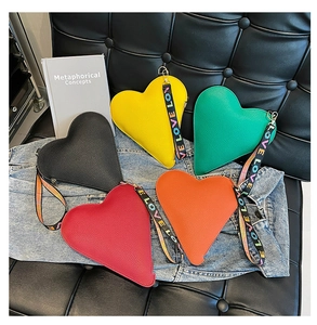 Detalle de cinco bolsos con forma de corazón en colores vivos y correa ancha estampada