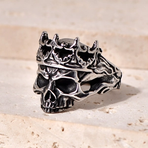 Gothic punk skull ring with crown in vintage silver finish on stone background