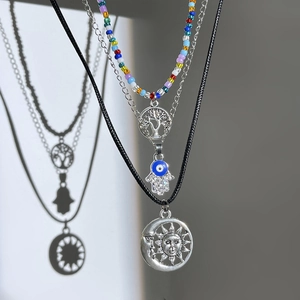 Detail of layered necklaces with Hamsa, Tree of Life, and Sun Moon pendants