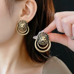 Gros plan de boucles d'oreilles tête de lion vintage en bronze avec anneau sur modèle