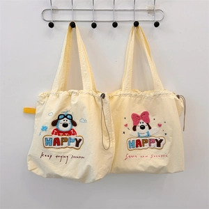 Detail of embroidered cartoon puppy patterns on cream canvas drawstring tote bags