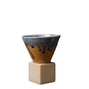 Handmade ceramic tapered mug with blue drip glaze and a minimalist wooden cube base