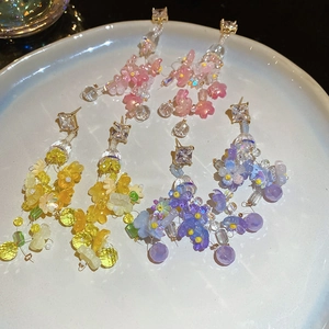 Detailed view of three pairs of floral tassel earrings in pink yellow and purple