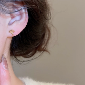 Gros plan d'une boucle d'oreille feuille de ginkgo dorée avec zircone sur modèle