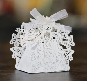 Macro shot of laser-cut butterfly hollow patterns on white candy box with ribbon