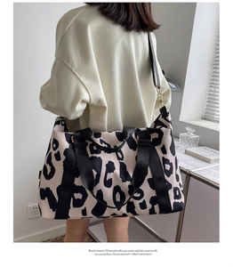Detail of waterproof cow print travel tote with wide nylon handles and adjustable strap