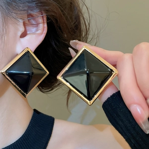 Gros plan de grandes boucles d'oreilles carrées en résine noire avec cadre en métal doré vintage