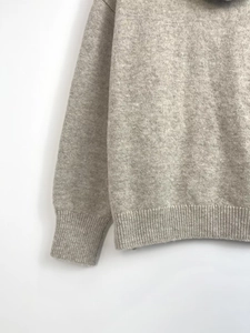 Close-up of oatmeal knit sweater showing rib-knit cuffs and soft wool blend texture