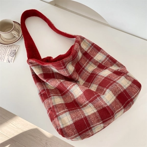 Macro shot of red plaid wool tote bag showing thick texture and soft material on white surface