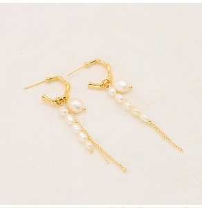 Detail of gold bamboo hoop earrings with white natural pearls and long tassel chains