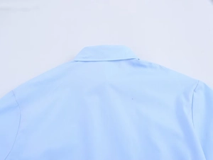 Détail du col de la chemise bleu clair et des coutures d'épaules au dos du haut