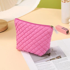 Detailed close-up of a pink quilted cosmetic bag with diamond pattern on a cozy desk