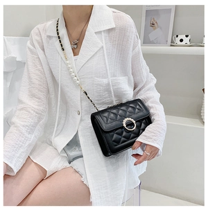 Close-up of quilted black crossbody bag with large pearl chain and elegant gold accents