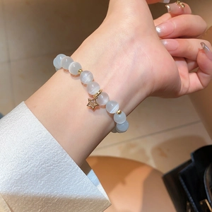 Detailed view of cat eye stone beaded bracelet with a zircon-studded gold star charm