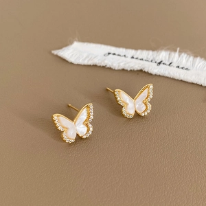 Detail of gold butterfly earrings with white mother-of-pearl wings and crystal borders