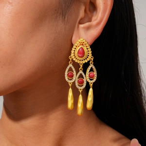 Détail de boucles d'oreilles style palais vintage avec pierres rouges et pompons