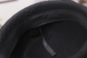 Detailed interior of a wool beret showing 100% wool label and mesh veil texture
