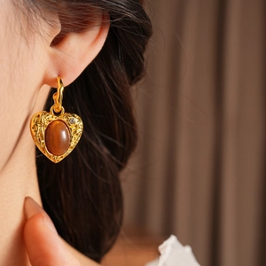 Detail of vintage heart-shaped golden earring with brown resin stone and small diamond