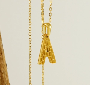 Close-up of 18K gold stainless steel necklace featuring a textured letter A pendant