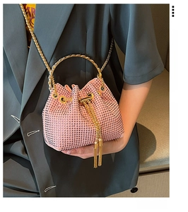 Detail of pink rhinestone bucket bag featuring gold metal handle and chain strap