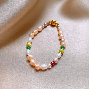 Détail d'un bracelet de perles baroques colorées avec fermoir doré sur tissu