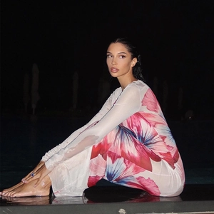 Detail of sheer mesh dress with vibrant floral print and long sleeves for summer beachwear