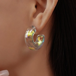 Close-up of a C-shape clear acrylic aurora earring worn to show its iridescent glow