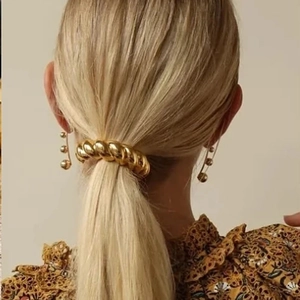 Detail of golden croissant hair ring and triple bead linear drop earrings on a model
