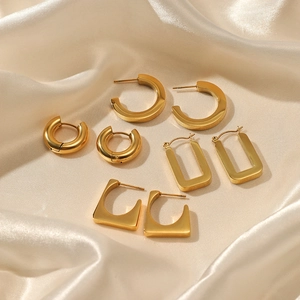 Set of four 14K gold plated geometric stainless steel earrings on beige silk fabric