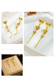Macro detail of gold-plated long tassel heart earrings with cascading heart charms
