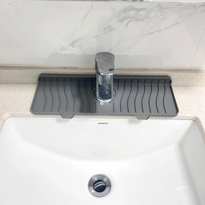 Close-up of grey silicone faucet splash guard with wavy drainage texture on sink