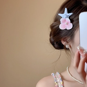 Detail of starfish and pink fabric flower hair clip with pearl on model's hair
