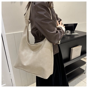 Detail of a large beige leather tote bag showing smooth texture and spacious bucket shape