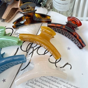 Detailed view of large resin hair claws in tortoiseshell and Morandi colors over magazines