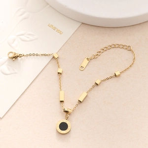 Detailed shot of a gold chain bracelet with Roman numeral pendant on a minimalist background