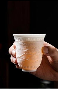 Detail of Dehua white porcelain teacup with relief dragon pattern and translucent texture