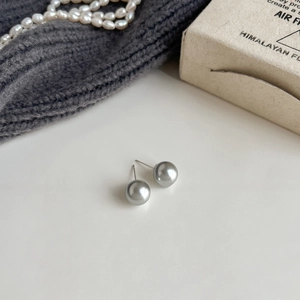 Detailed view of gray pearl studs with metallic luster on a minimalist silver needle post
