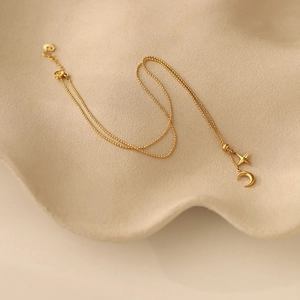 Macro detail of gold plated bead chain necklace with crescent moon and star charms