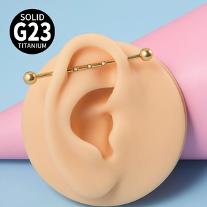 Détail macro du piercing industriel en titane G23 doré avec trois opales blanches