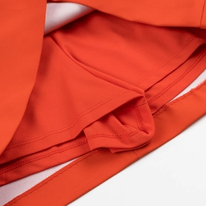 Dettaglio ravvicinato della gonna-pantalone arancione con pantaloncini di sicurezza