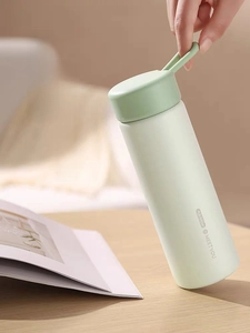 Detail showing mint green insulated water bottle with silicone carry handle and matte finish
