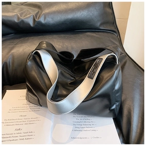 Detailansicht der schwarzen Leder-Pillow-Bag mit silbernem Gurt auf einem Sofa