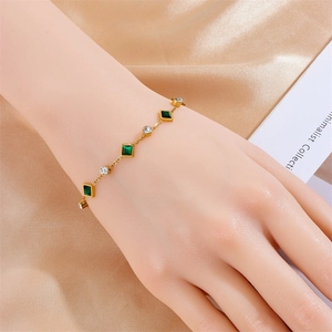 Detail of gold-plated bracelet with square emerald stones and round cubic zirconia on silk