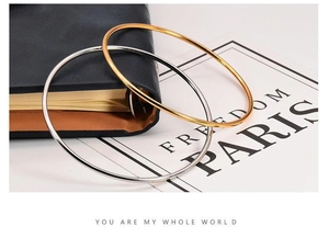Minimalist 2mm gold and silver titanium steel bangles stacked on a vintage book