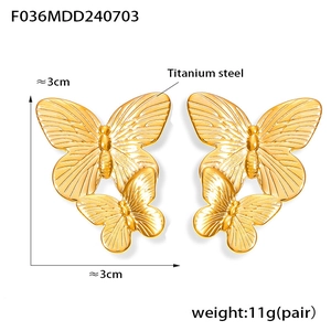 Macro detail of gold double-layered butterfly earrings in titanium steel with radial textures