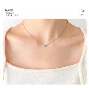 Detail of single zircon pendant necklace in silver finish on a woman's collarbone