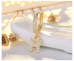 Macro detail of gold-plated S925 silver earring featuring a micro-paved letter H charm
