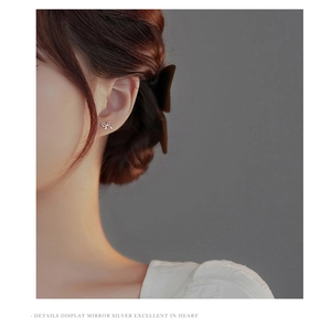 Detailed close-up of a silver bow earring worn on ear with premium mirror finish